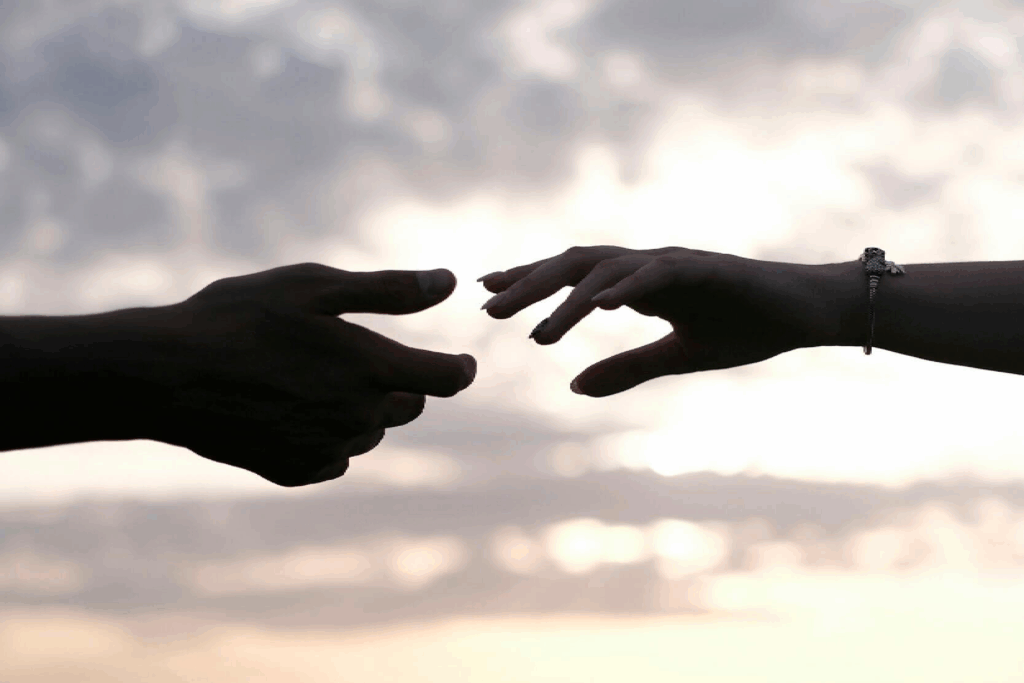hands reaching at sunset